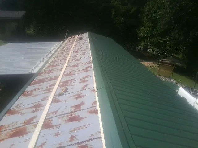 Old rusted panels beside newly installed green metal roofing — Wind Damage Roof Repair by Roofing Brothers in Dodgeville
