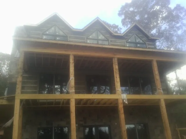Dormers and porch framing on a large log home under construction — Roof Coating work by our crew in Dodgeville