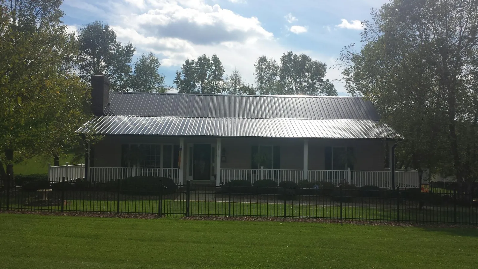 Gray metal roof on a brick ranch with a full width front porch — Gutter Guard Installation work by our crew in Dodgeville