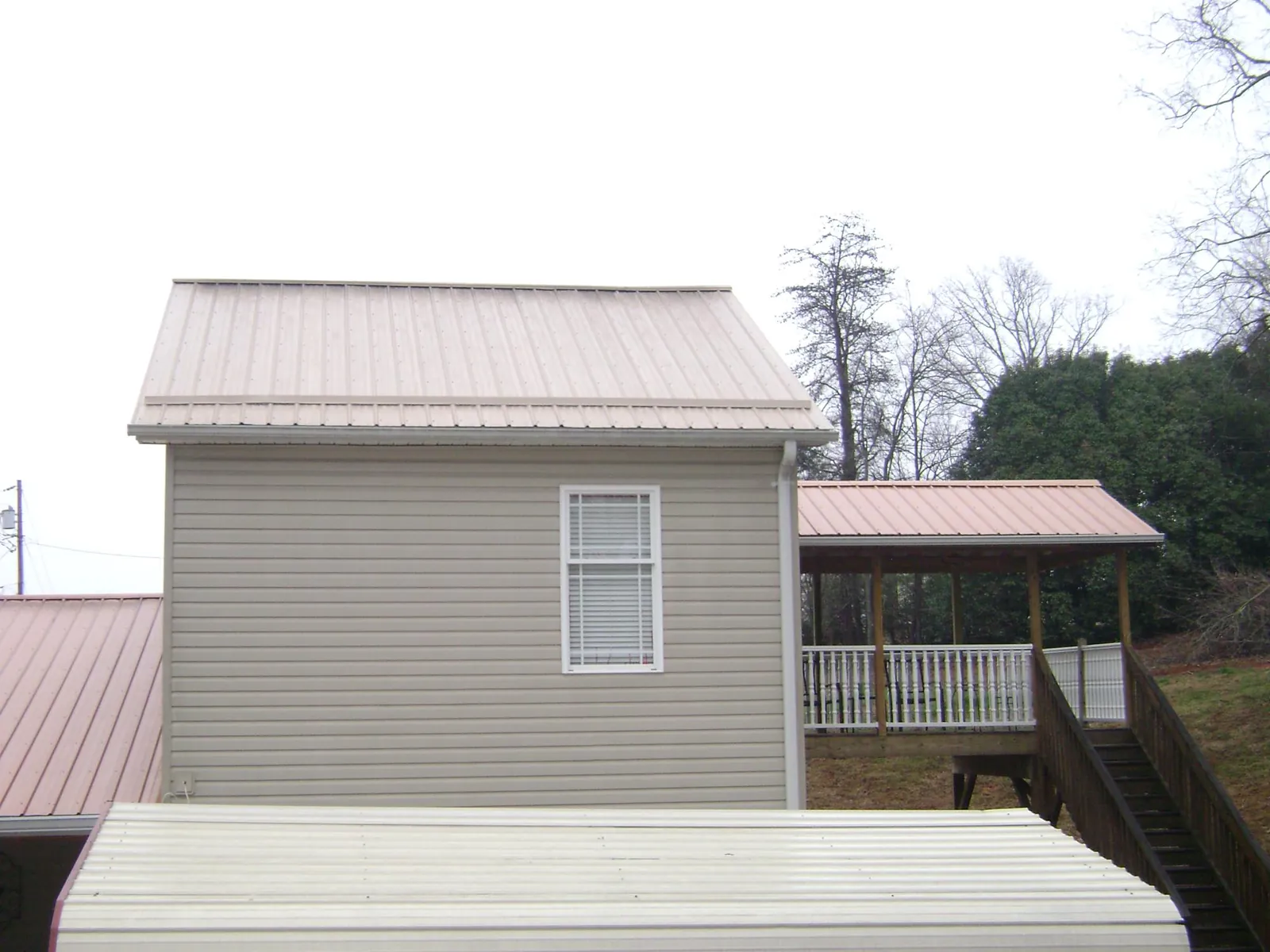 Tan metal roofs on a two story addition and attached porch, from a Roof Replacement job in Dodgeville