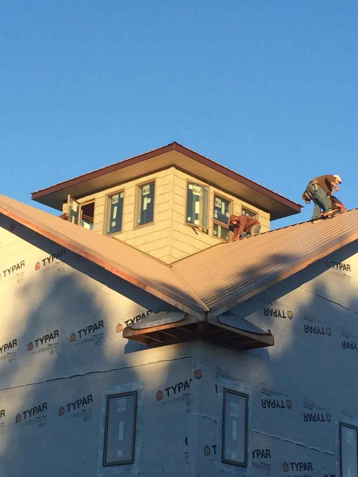 Roofers working around a rooftop cupola on a new metal roof at sunset — Roof Waterproofing in Dodgeville by Roofing Brothers